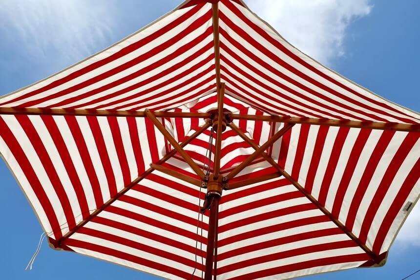 Image, red and white striped umbrella against a blue sky