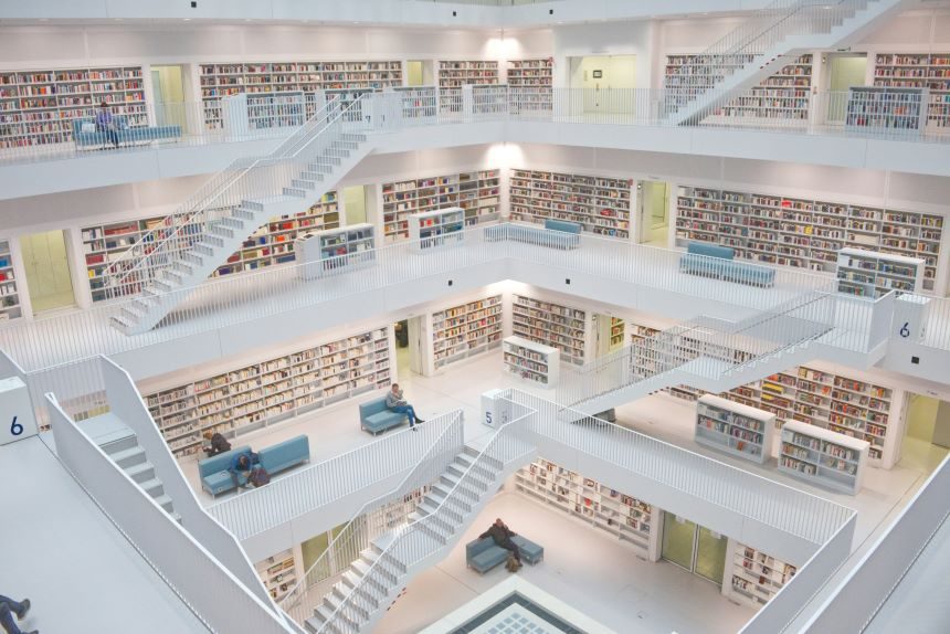 Wide shot of a multi-level library with white staircases and bookshelves.